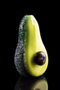 Glass avocado-shaped pipe with a dark, marbled sphere as the bowl, reflecting on a glossy black surface.