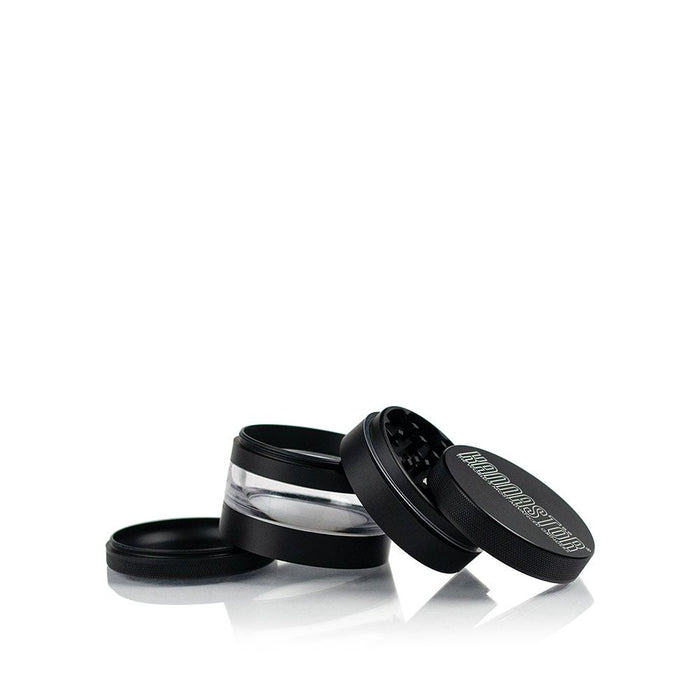 A partially open Kannastor 2.5" 4-Piece Grinder with Monofilament EZ Screen is displayed at a slight angle on a dark surface.