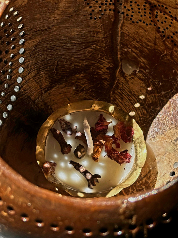 A lit tea light candle in a coconut shell candle.