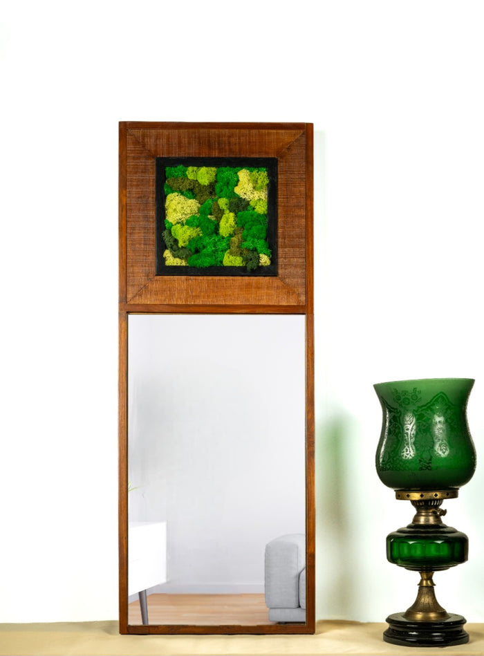 A rectangular mirrored wall art piece with a green mossy panel set within a wooden frame, accompanied by a decorative vase with a green floral pattern.