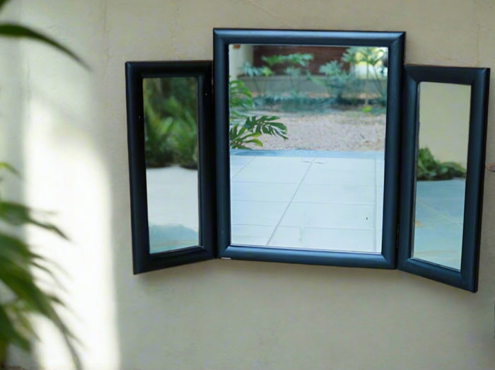 A large rectangular colonial-style foldable mirror made of teak wood, with a reflective surface and visible wood grain, placed on a floor near a wall.