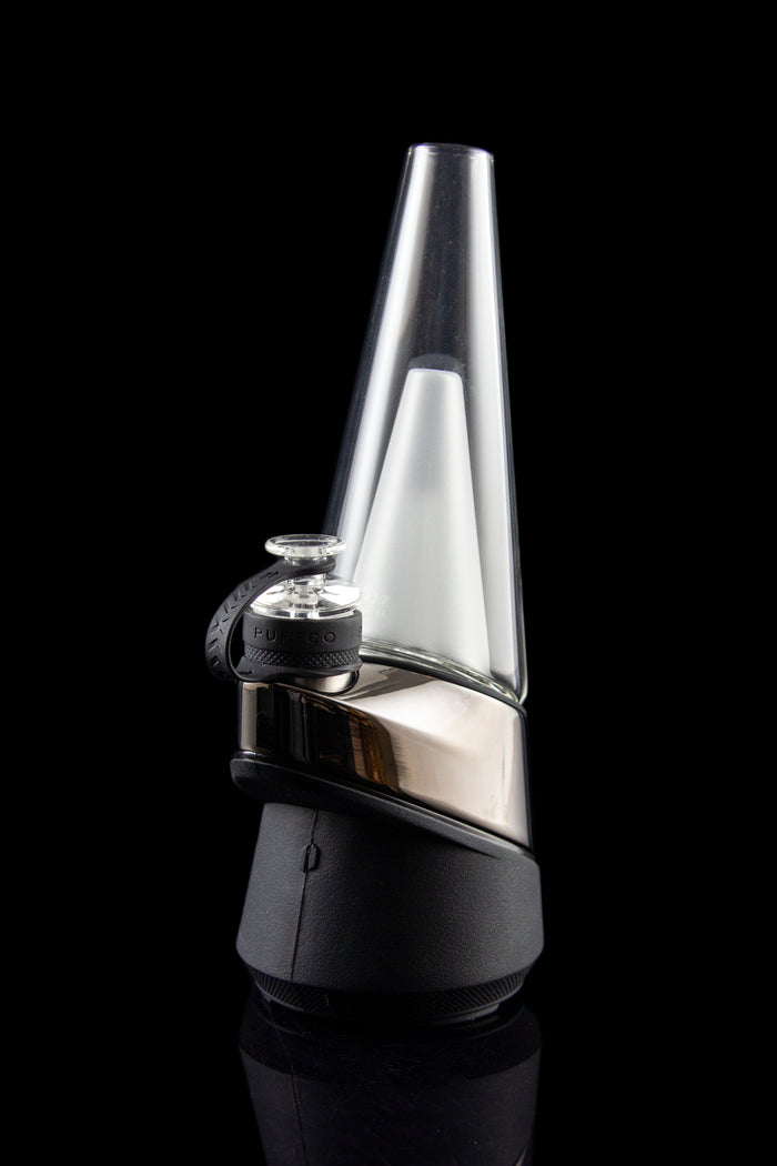 Sleek, black and silver cannabis e-rig vaporizer with a glass water pipe attachment, displayed on a reflective surface.