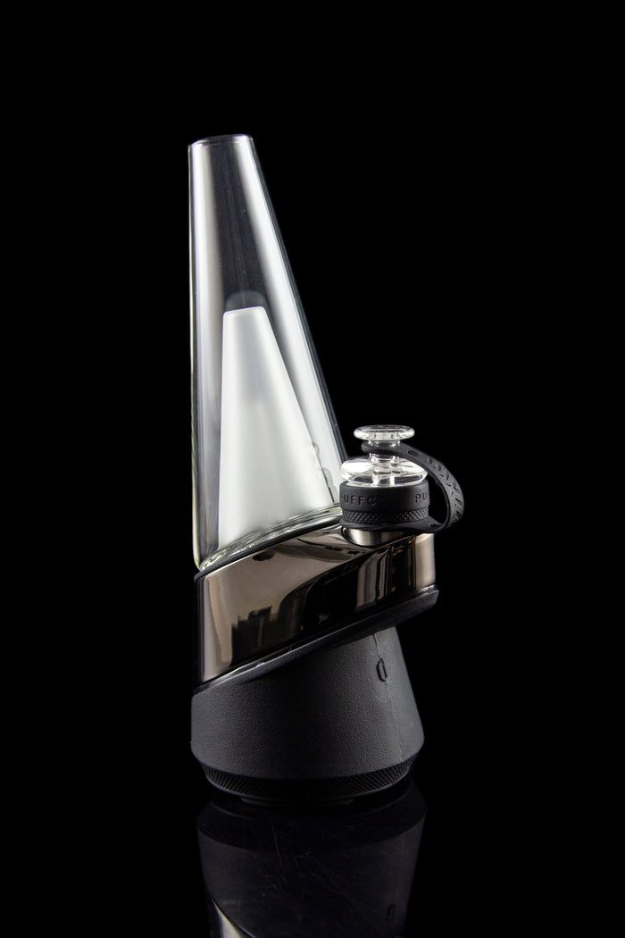 Sleek, black and clear glass cannabis e-rig vaporizer against a dark background.