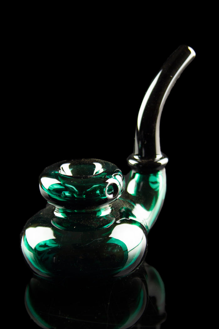 Emerald green glass bubbler with intricate swirls, reflecting on a dark surface.