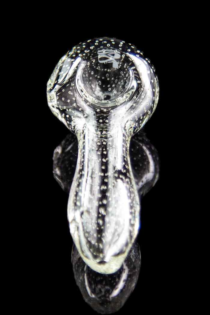 Clear glass bubbler pipe with speckled pattern, reflecting on a dark surface.