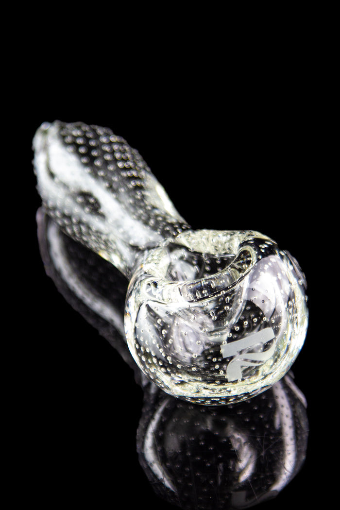 Clear glass pipe with textured surface and reflective black background.