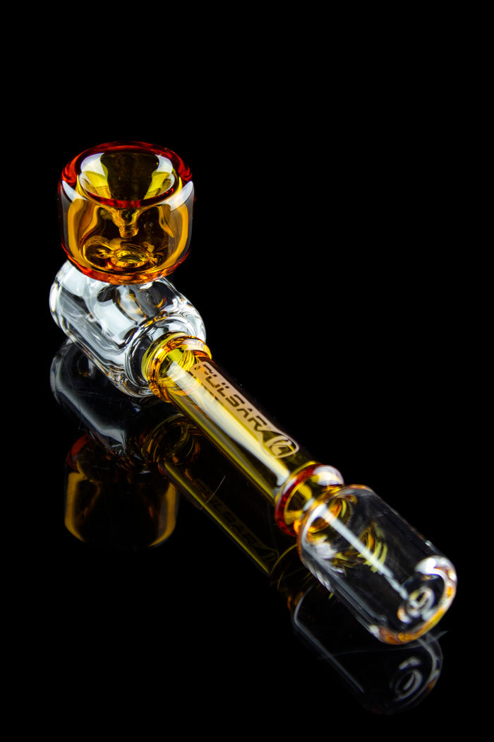 Glass cannabis pipe with orange and clear glass, reflected on a black surface.