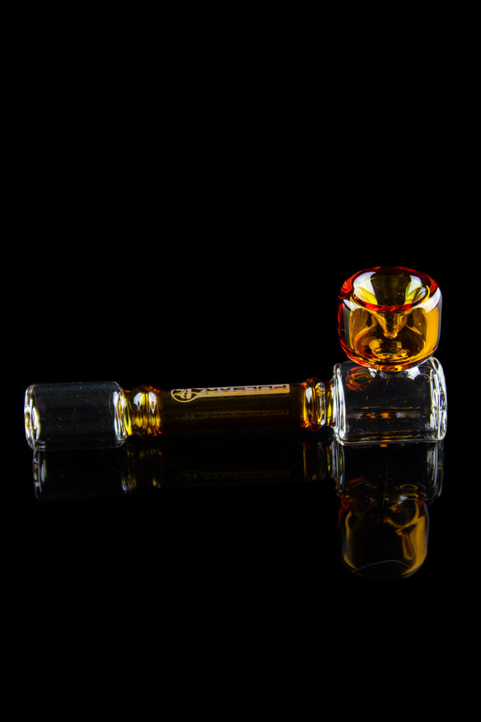 Amber glass cannabis oil rig with reflective surface.