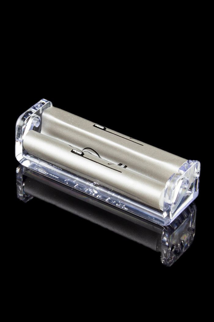 Clear acrylic rolling machine for making cigarettes, isolated on a black background.