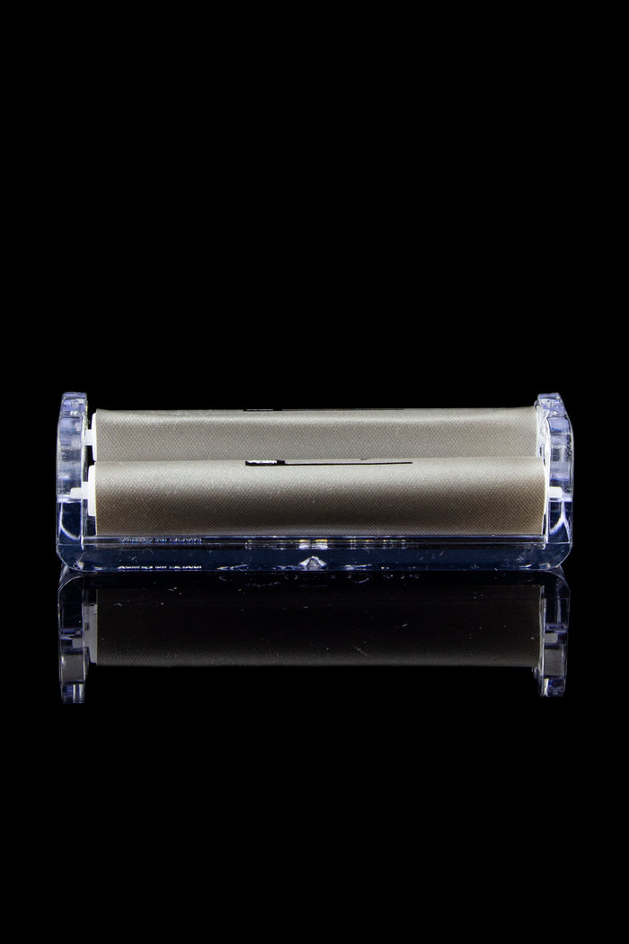Sleek gold cannabis storage container encased in clear acrylic, with a mirrored reflection on a black surface.