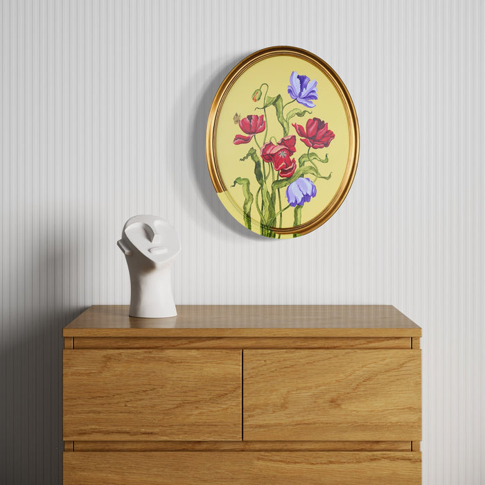 The artwork 'Tulips and Wings III' by Carlos Gamez de Francisco features vibrant red tulips and purple iris flowers against a soft yellow background, housed in an elegant oval gold frame. The flowers are rendered in delicate brushstrokes with graceful green stems, showcasing a botanical illustration style in acrylic on canvas.