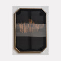 The artwork 'Untitled 104' by Victoria Manganiello features a minimalist fiber composition with a horizontal band of copper-toned weaving across charcoal black background. The textural piece, framed in a geometric wooden border, showcases natural and synthetic fibers creating an abstract horizon-like effect, with subtle variations in weave density.